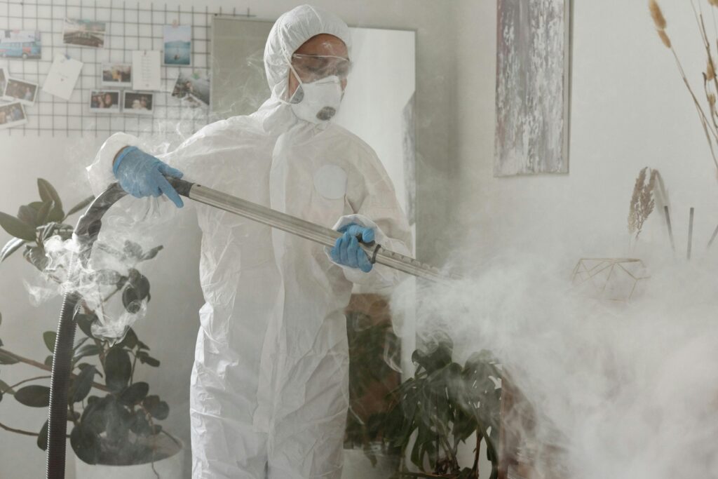 Person in PPE fumigating indoors for health safety during COVID-19.